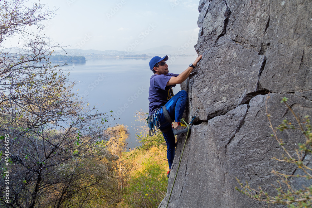 Young Hispanic man with a rope engaged in the sports of rock climbing on the rock