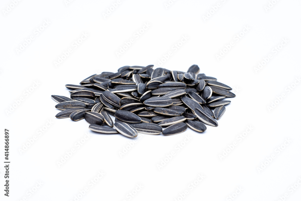 A pile of black sunflower seeds on a white background A pile of black sunflower seeds on a white background