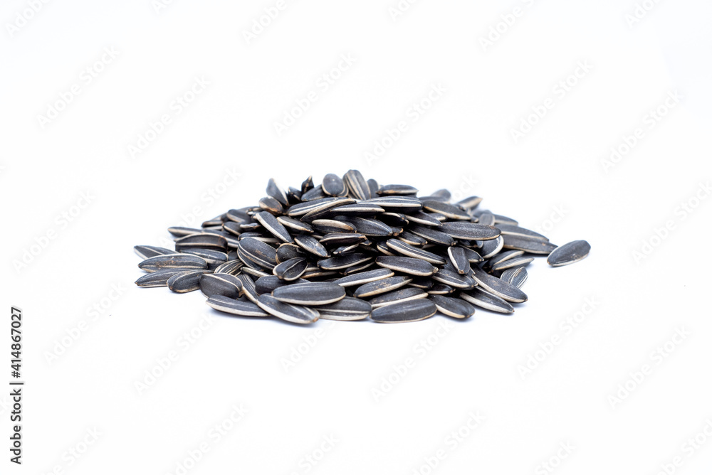A pile of black sunflower seeds on a white background A pile of black sunflower seeds on a white background