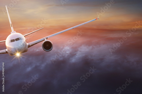 Commercial airplane jetliner flying above dramatic clouds in beautiful light. Travel concept.