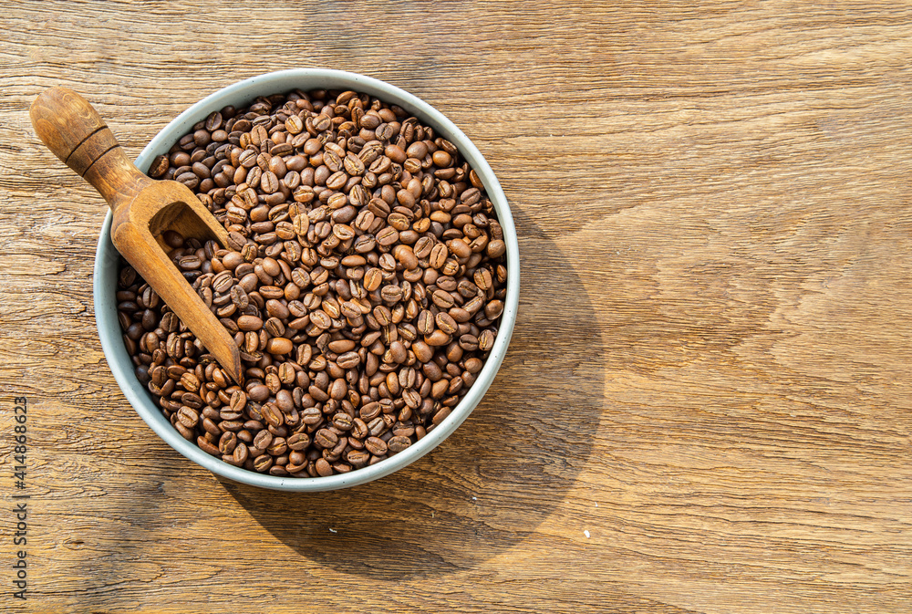 Coffee beans with old wooden scoop on the ceramic plate put on wooden background with copyspace for your text. Alternative coffee for living life, Coffee style, Selective focus. Coffee beans with old wooden scoop on the ceramic plate put on wooden background with copyspace for your text. Alternative coffee for living life, Coffee style, Selective focus.