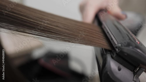 The process of straightening hair in the salon with the help of a steampod. High quality 4k footage. Straightening the hair of a brunette with a black steampod. photo