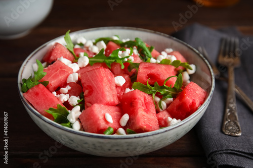 Delicious salad with watermelon, cheese and arugula on wooden table, closeup