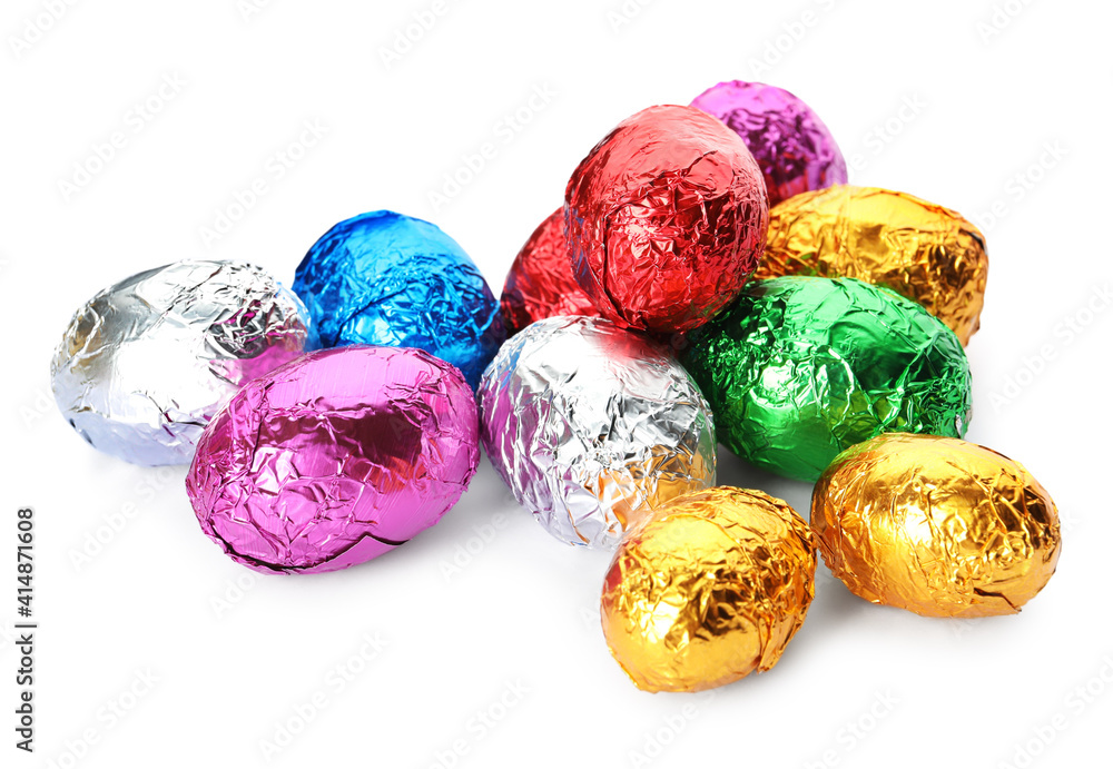 Many chocolate eggs wrapped in bright foil on white background