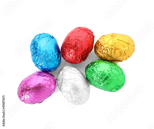 Many chocolate eggs wrapped in bright foil on white background, top view