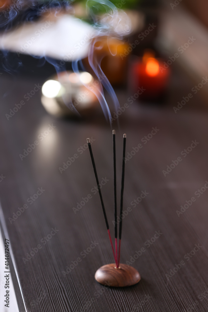 Incense sticks smoldering on wooden table in room Incense sticks smoldering on wooden table in room