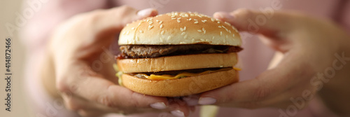 Female hands hold hamburger close-up. Fast food restaurants concept.