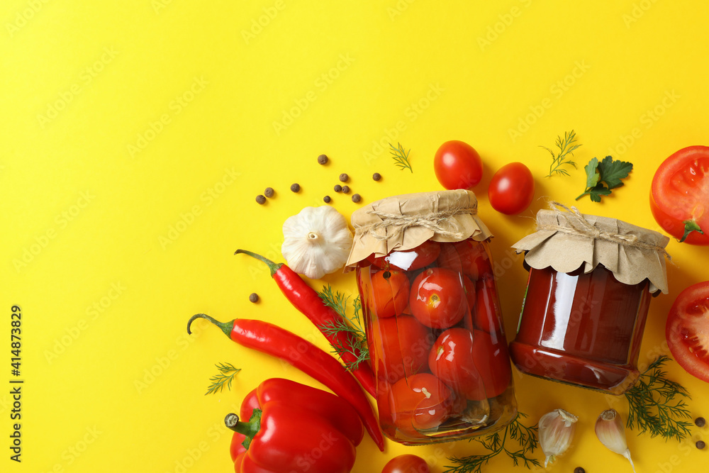 Pickled tomatoes and ingredients on yellow background