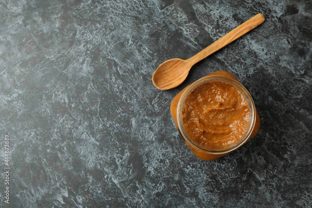 Jar with zucchini caviar and wooden spoon on black smokey background Jar with zucchini caviar and wooden spoon on black smokey background