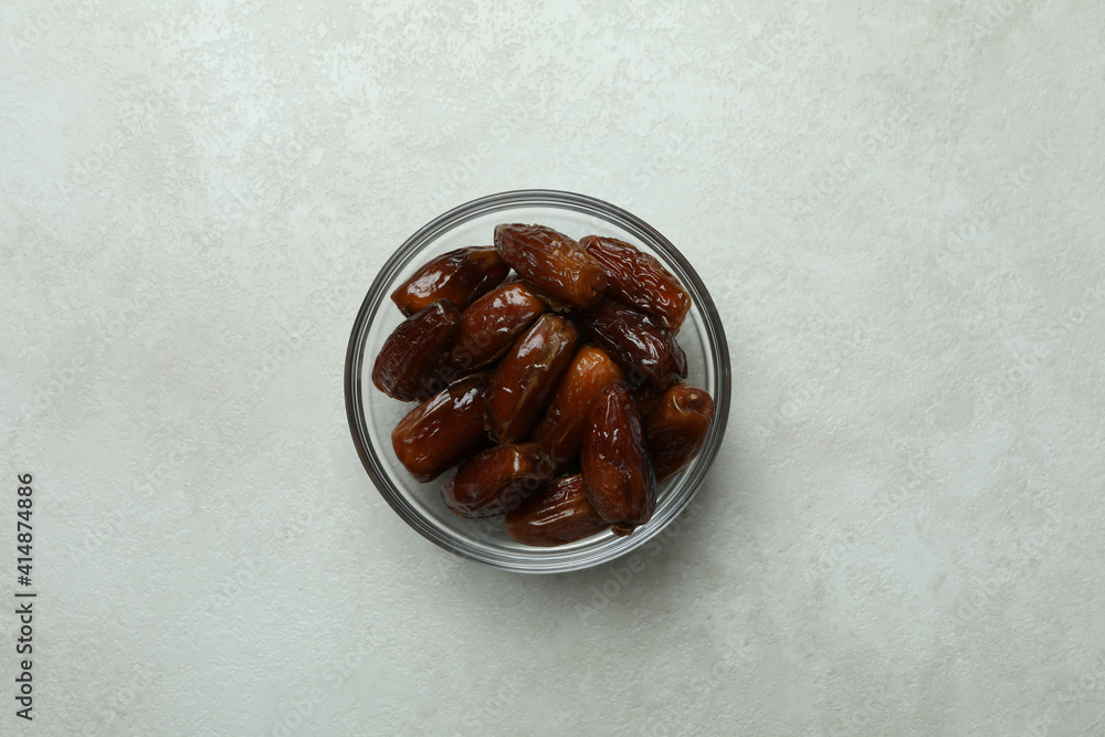 Glass bowl of dates on white textured background Glass bowl of dates on white textured background