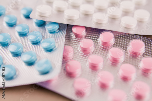 tablets of different colors in blisters on the background of medicines