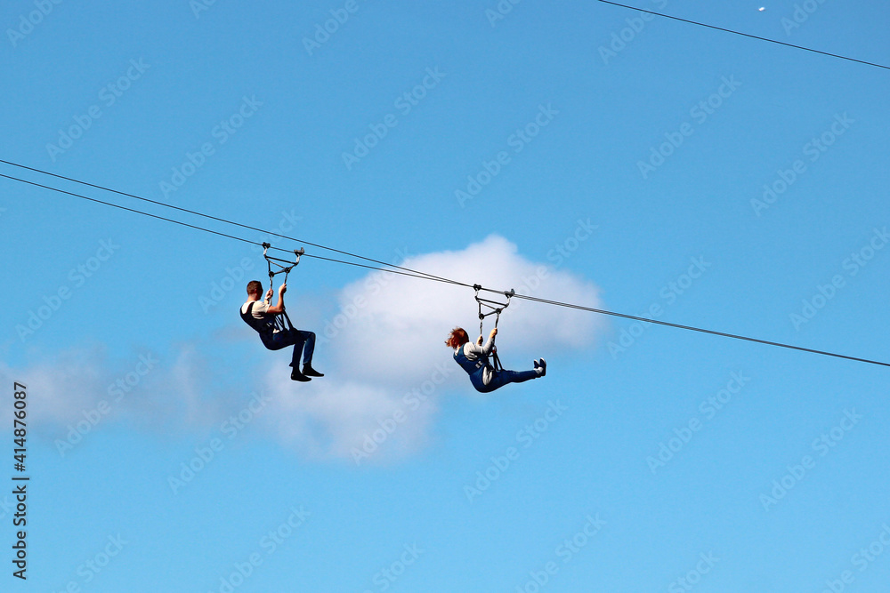 Man and woman descend on a zipline Man and woman descend on a zipline