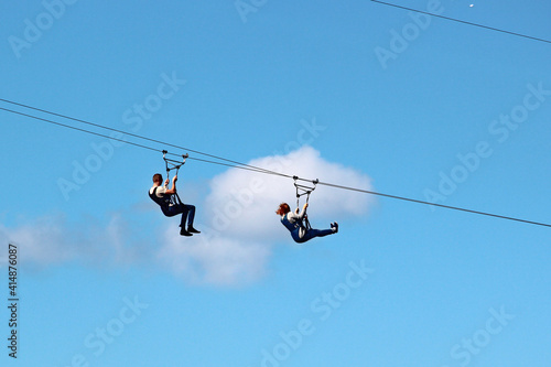 Man and woman descend on a zipline