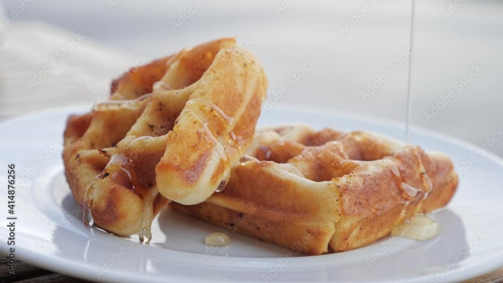 Honey pouring on a waffles. Waffles with hot maple syrup, Sweet breakfast food, unhealthy eating. Sugar food Honey pouring on a waffles. Waffles with hot maple syrup, Sweet breakfast food, unhealthy eating. Sugar food