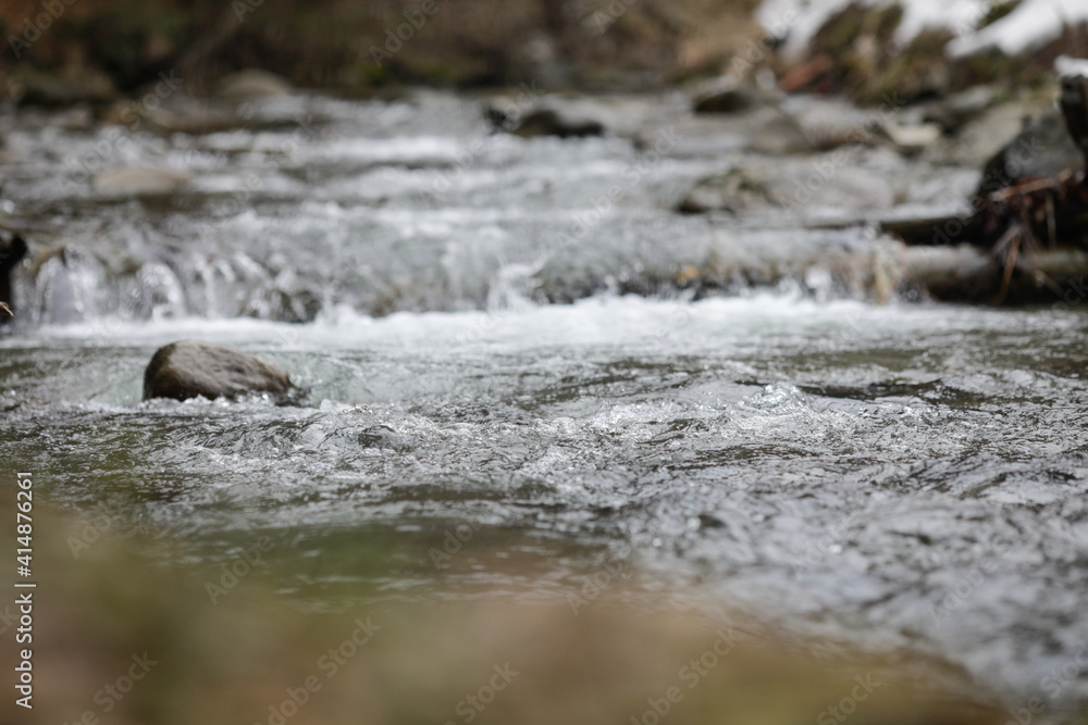 Obraz premium Details with the clear water of a running mountain stream during a cold and sunny winter day in the Romanian Carpathian Mountains.