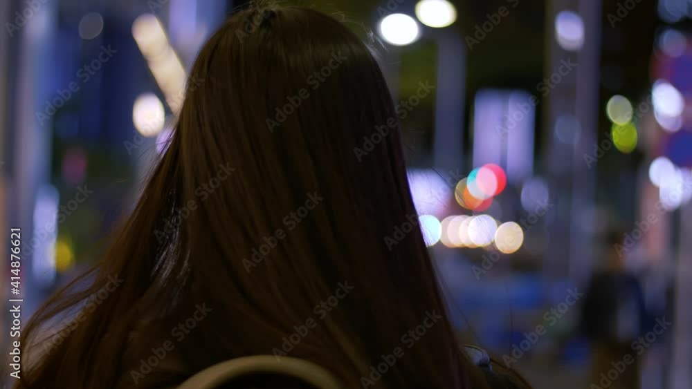 Slow motion rear head shot with bokeh of a young, Asian female tourist walking around a city at night. Slow motion rear head shot with bokeh of a young, Asian female tourist walking around a city at night.