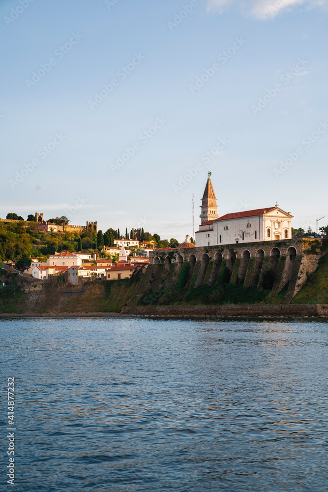 Obraz premium Piran at sunset, view from the sea toward the old town and church Slovenia, Europe