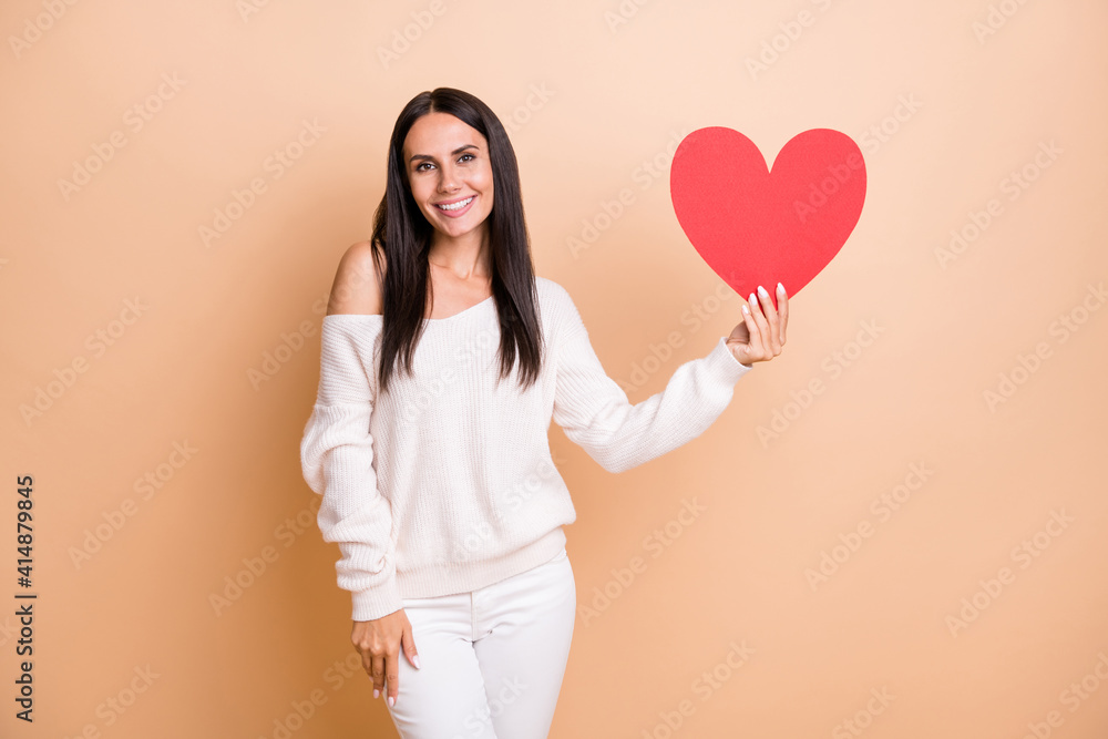 Photo of young attractive girl happy positive smile hold big paper heart romantic feelings isolated over beige color background Photo of young attractive girl happy positive smile hold big paper heart romantic feelings isolated over beige color background
