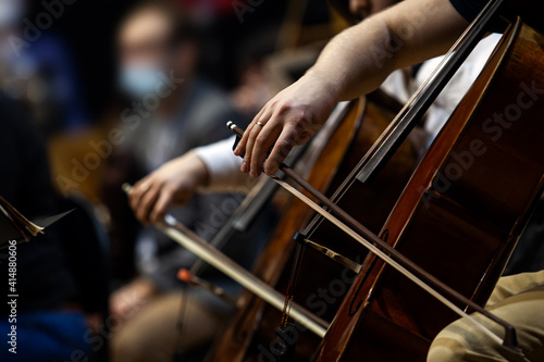 Hands of a musician playing cello in an orchestra