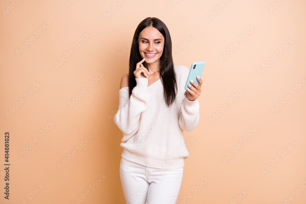 Photo of young cheerful woman happy positive smile look browse cellphone chat type isolated over beige color background Photo of young cheerful woman happy positive smile look browse cellphone chat type isolated over beige color background