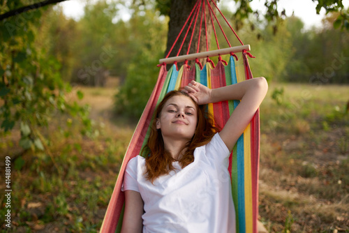 happy woman lies in a hammock outdoors in the forest laughing