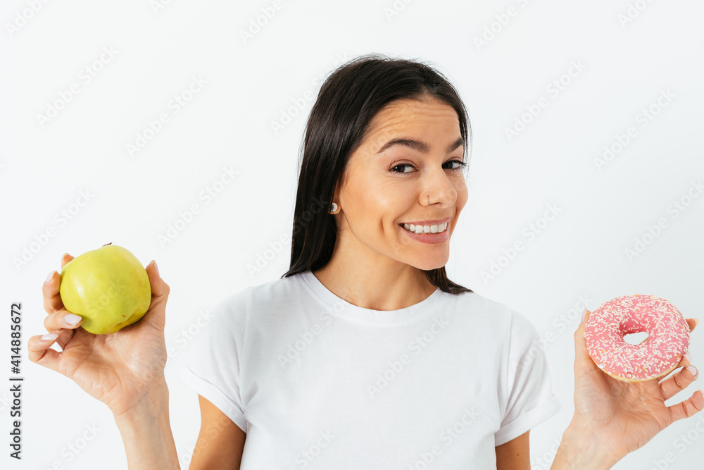 Close-up portrait young woman holding donut and apple in her hands Close-up portrait young woman holding donut and apple in her hands