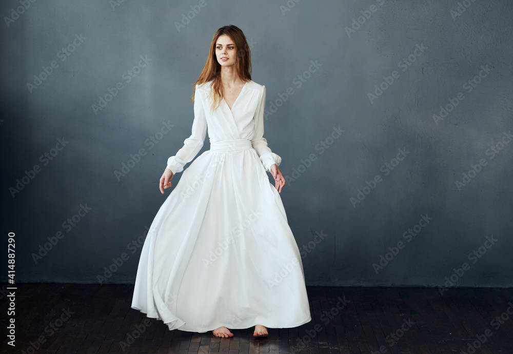 Woman on a gray background in a white dress dance model in full growth