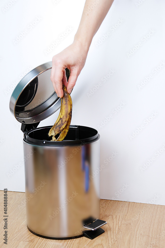 Αυτοκόλλητο Woman hand throwing a banana peel into the garbage bin