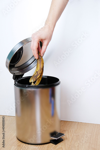 Fotografia Woman hand throwing a banana peel into the garbage bin