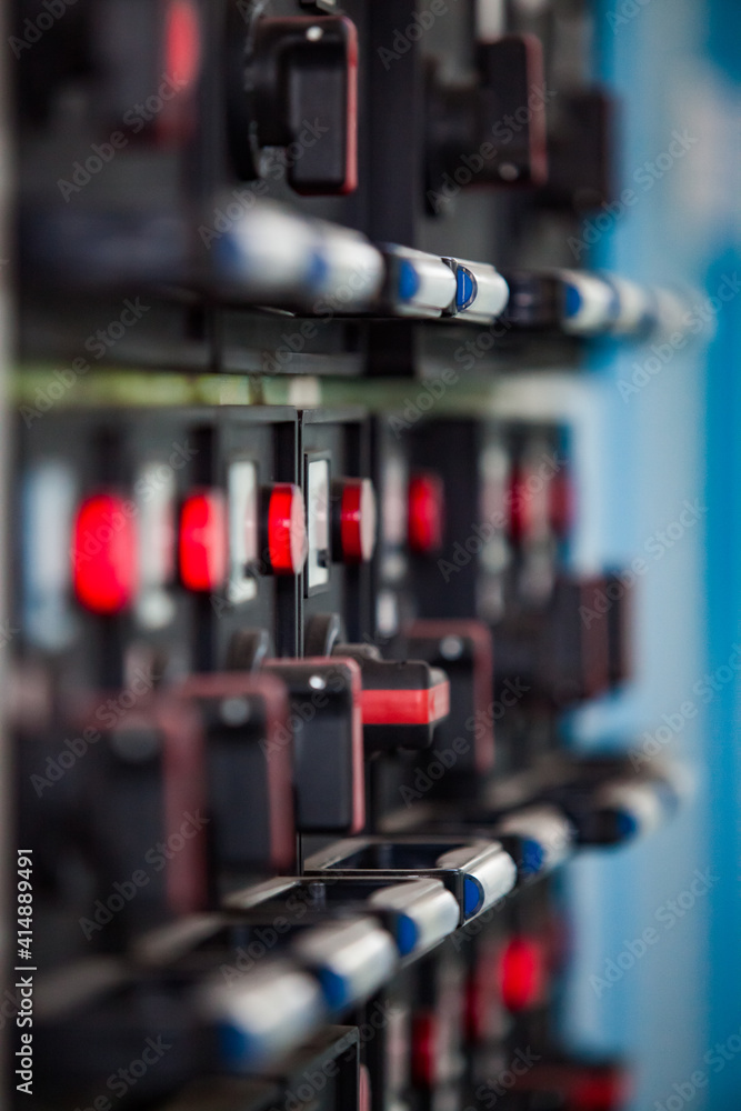Electric switchers on control panel. Red indicators lamps light on. Low depth of field, blurred background.