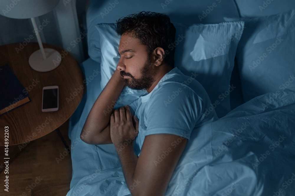 people, bedtime and rest concept - indian man sleeping in bed at home at night people, bedtime and rest concept - indian man sleeping in bed at home at night