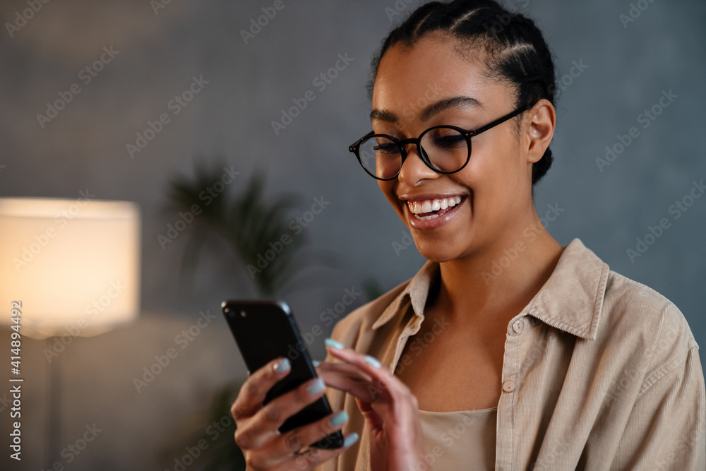 Cheerful african american woman using mobile phone and smiling Cheerful african american woman using mobile phone and smiling