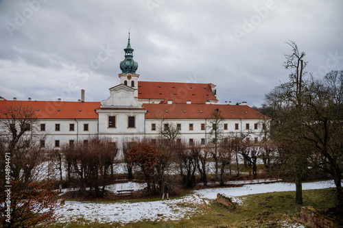 Baroque white benedictine monastery Brevnov with church, Medieval Basilica of St. Marquette, Garden and park, abbey under snow in winter day, Prague, Czech Republic photo