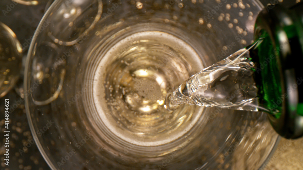 Champagne pouring in a glass from a bottle, top view, close-up Champagne pouring in a glass from a bottle, top view, close-up