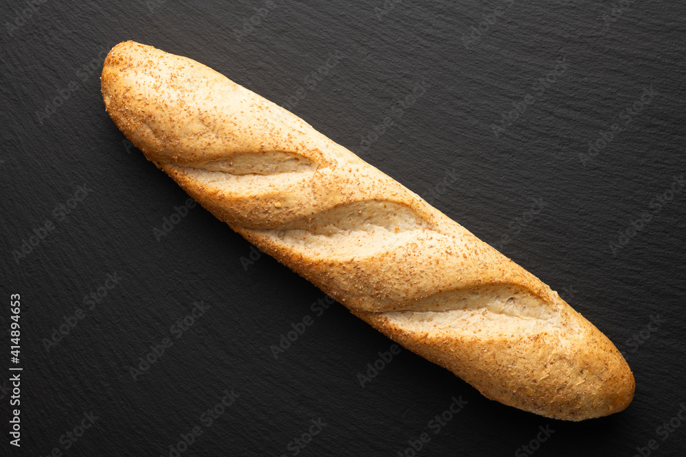 french baguette with bran on a dark stone background