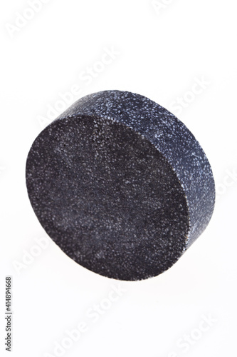 Black round piece of soap on a white background. 
