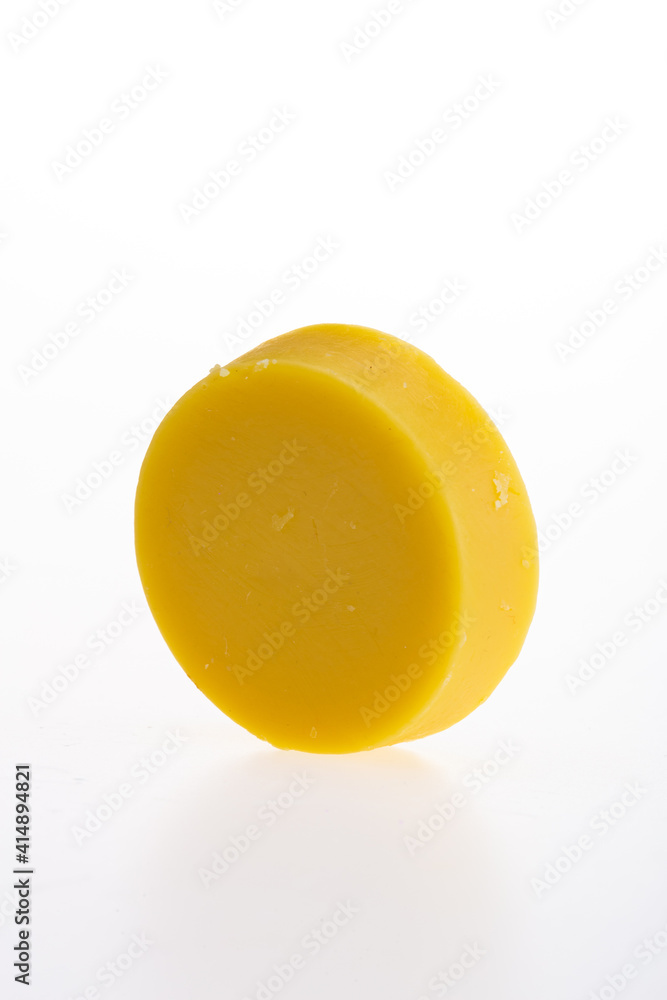 Yellow round piece of soap on a white background. 