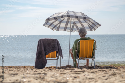 Alone man sitting on the beach under umbrella, sea backgorund.