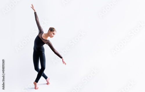 Photography a ballet girl in a black tight-fitting suit dances on a white background with mo