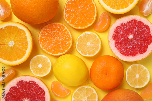 Many fresh citrus fruits on yellow background  flat lay