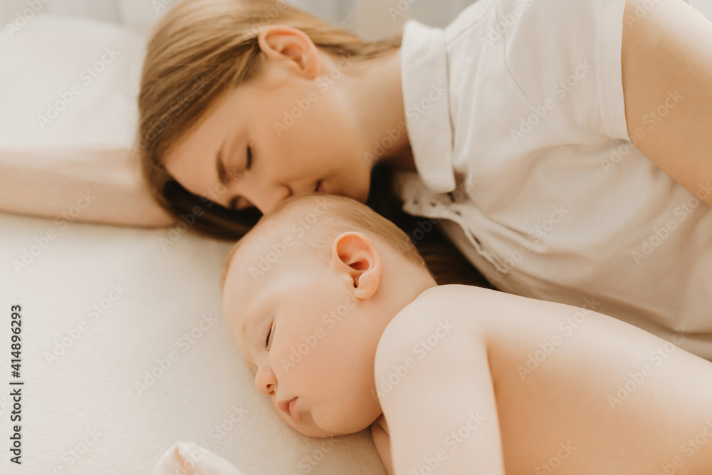 Side view of beautiful young mother and her cute little baby sleeping in bed Side view of beautiful young mother and her cute little baby sleeping in bed
