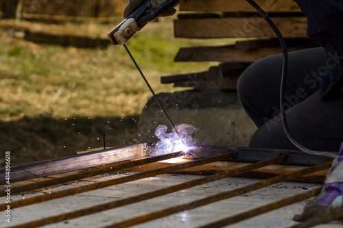 welding of a metal framework, works take place on the street, the process of welding of metal is visible in a close-up.