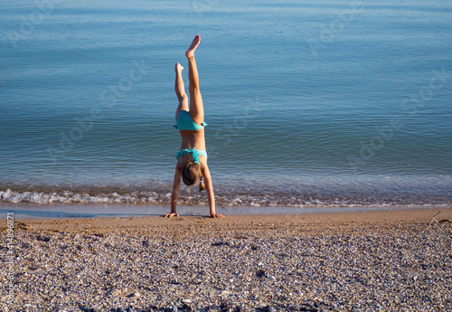 Fototapet The girl does gymnastics in the fresh air on the beach