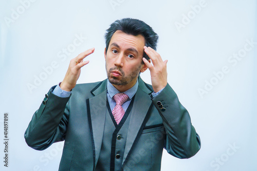 A man with tousled hair in a business suit straightens his hair