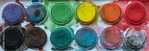Close up view of messy colorful watercolor palette.