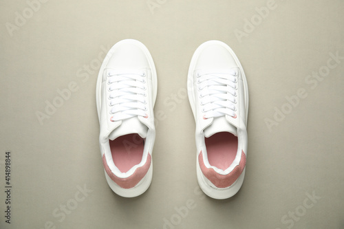 Stylish white sneakers on grey background, top view