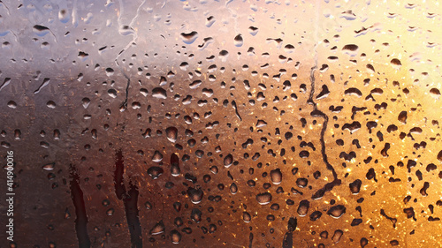 Horizontal natural background with water drops on the window with sunbeams, condensation on the glass with dripping drops