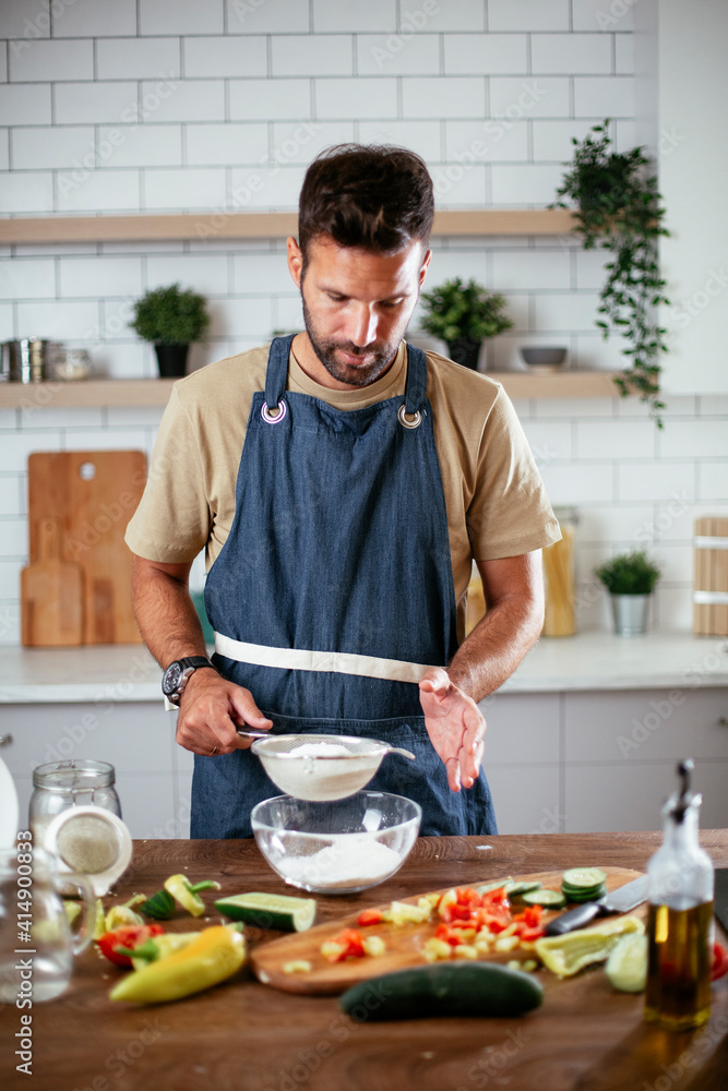 Happy man baking in the kitchen. Man making delicious food at home Happy man baking in the kitchen. Man making delicious food at home
