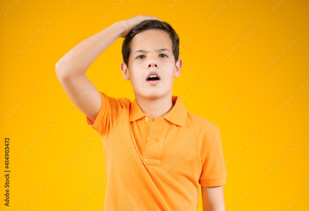 Handsome teen boy covers his head with his hand, isolated on orange background Handsome teen boy covers his head with his hand, isolated on orange background