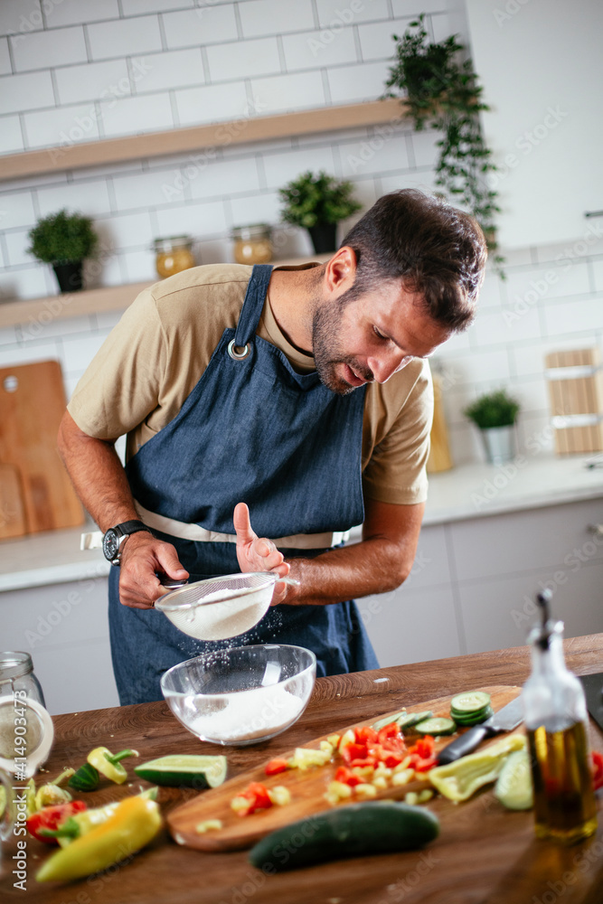 Happy man baking in the kitchen. Man making delicious food at home Happy man baking in the kitchen. Man making delicious food at home